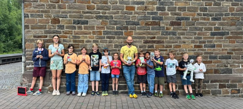 Roboter bauen Gruppenbild der Workshopteilnehmer mit ihren selbstgebastelten Robotern in der Hand. Sie stehen vor dem Jugendtreff in Daaden.