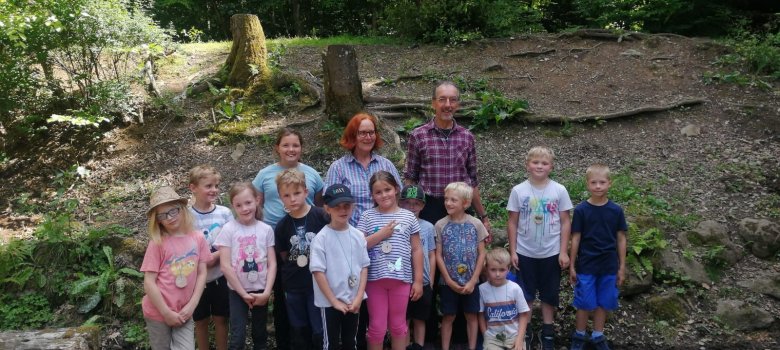 Wildnis Gruppenbild der Workshopteilnehmer im Wald . Im Hintergrund sind Baumstümpfe, Sträucher und Farn zu erkennen.