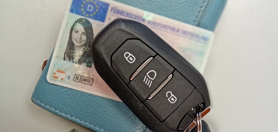Ein blaues Portmonnaie, eine deutscher Führerschein und ein Autoschlüssel.