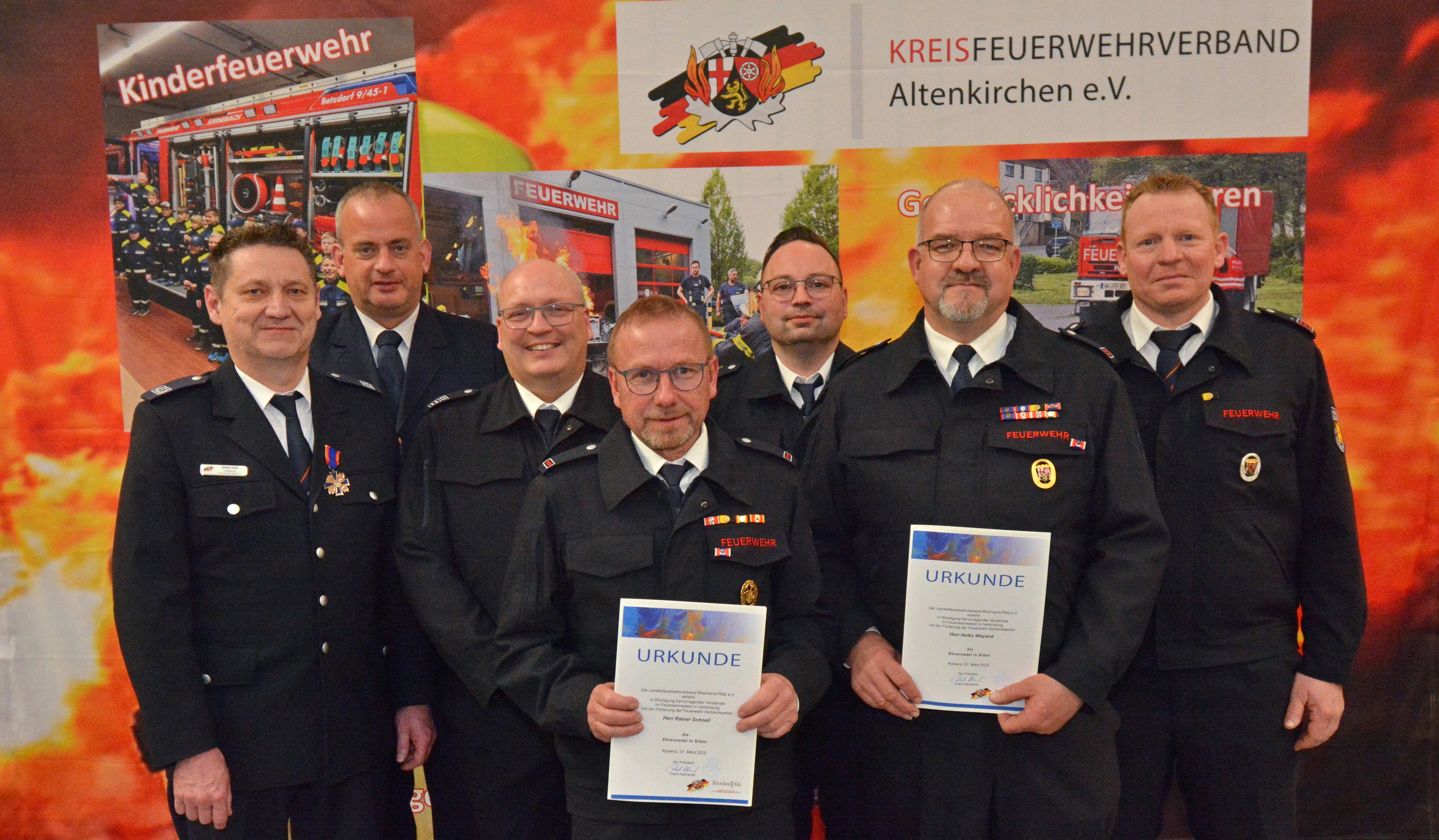 Hier sehen Sie Rainer Schnell und Heiko Weyand, die die silberne Ehrennadel des Landesfeuerwehrverbandes erhalten haben. Eingerahmt werden sie von den Grantulanten Volker Hain (1. Vorsitzender KFV); Ralf Schwarzbach (Brand- und Katastrophenschutzinspekteur); Matthias Theis (Wehrleiter); Michael Klein (stellv. Wehrführer LE Niederdreisbach-Schutzbach) und Florian Knautz (stellv. Wehrführer LE Weitefeld).