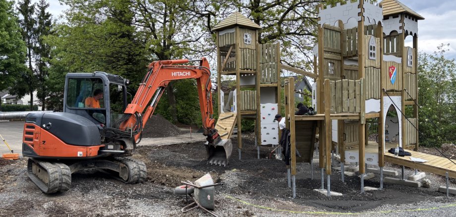 Bagger auf einem Spielplatz für einem neu errichteten Kletterturm für Kinder.