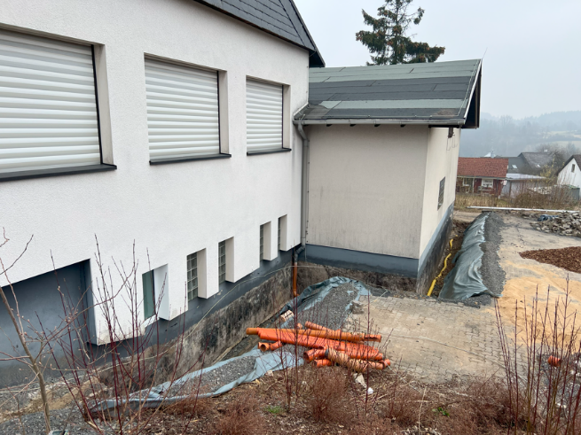 Hier sehen Sie die sanierungsbedürftige Stelle am Sockel des Bauhofgebäudes in Weitefeld vom oberen Parkplatz aus.