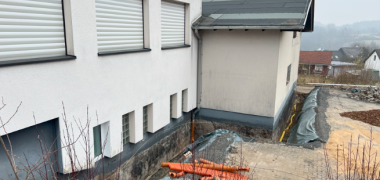 Hier sehen Sie die sanierungsbedürftige Stelle am Sockel des Bauhofgebäudes in Weitefeld vom oberen Parkplatz aus.