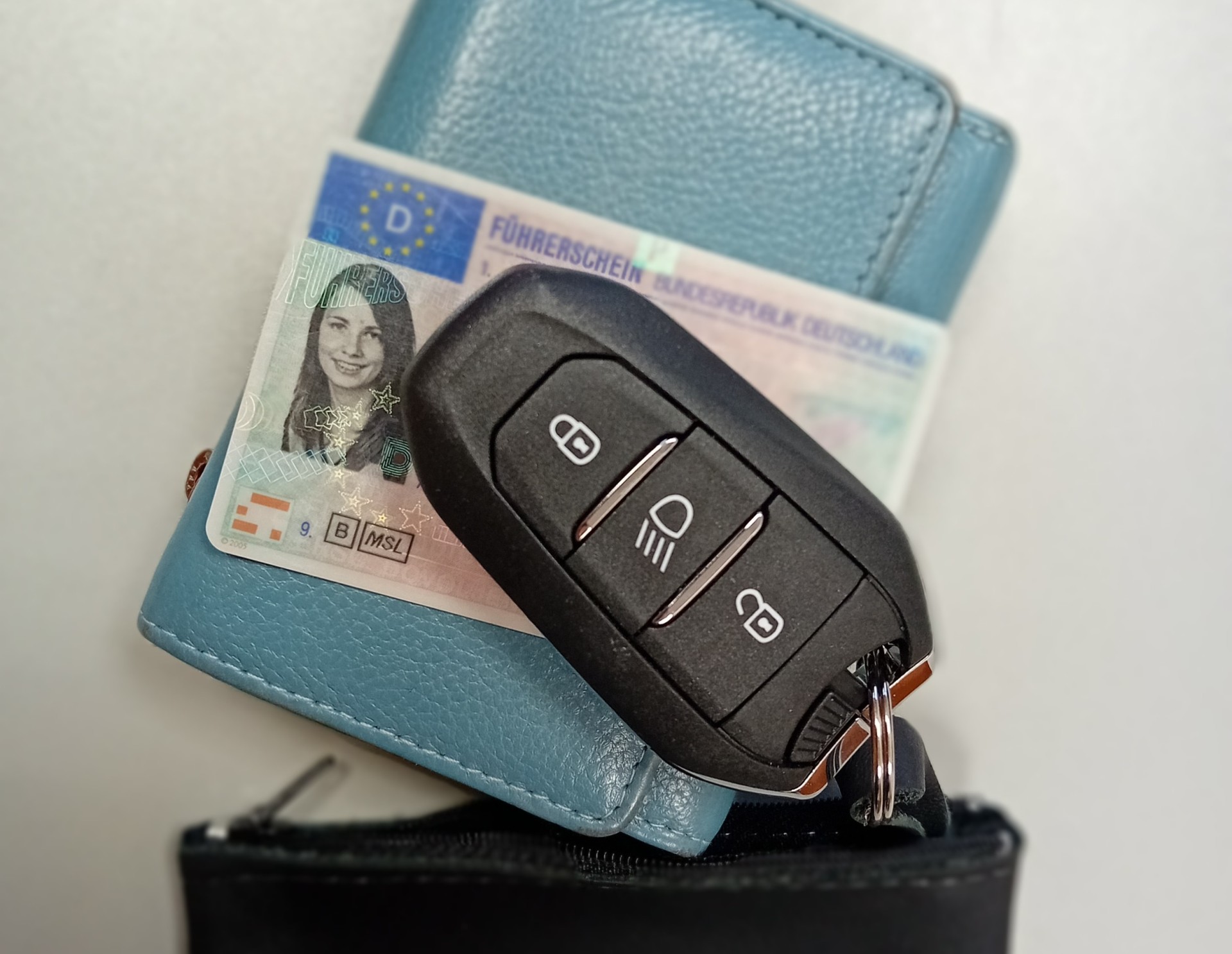 Ein blaues Portmonnaie, eine deutscher Führerschein und ein Autoschlüssel.