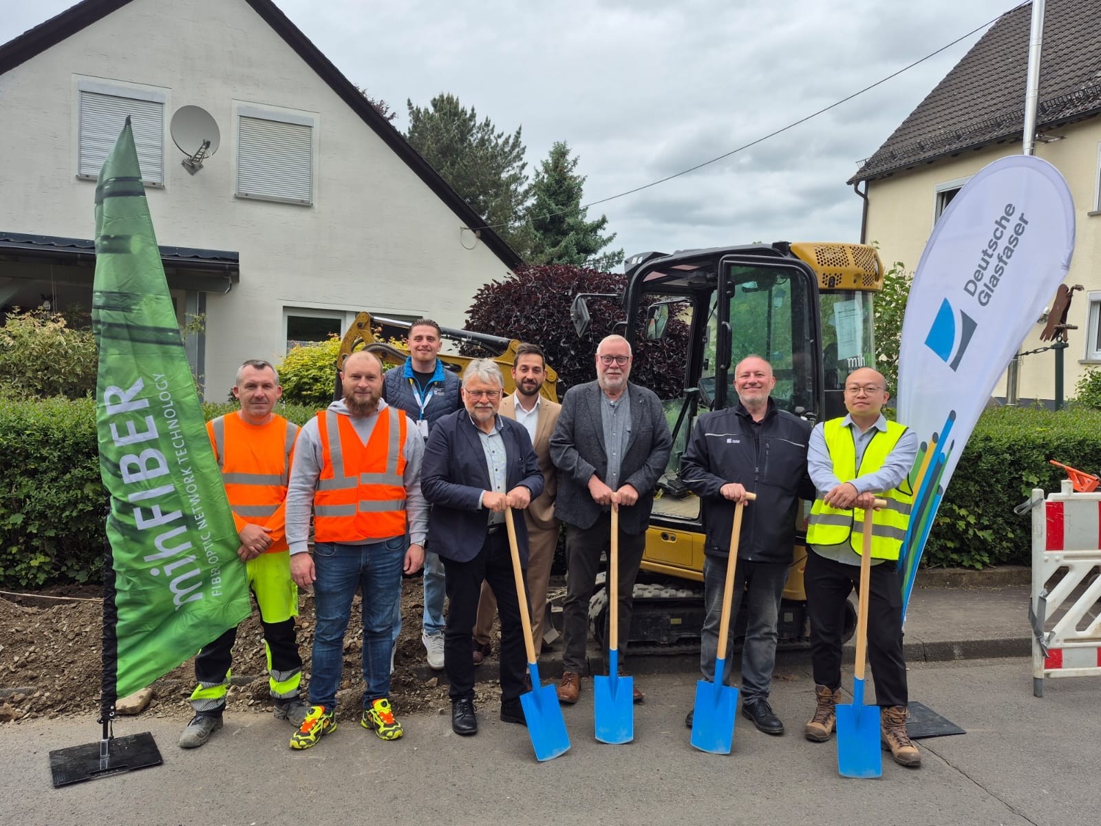 Hier sehen Sie Alessandar Chergovski (Bauleiter MIH), Nermin Kurahovic (Projektleiter MIH), Dustin Kocaa (Panda Promotion), Helmut Stühn (Bürgermeister), Sezer Carikci (Projektmanager FttH Vertrieb), Walter Strunk (Stadtbürgermeister Daaden), Dirk Peschel (Senior Manager kommunale Kooperationen), Eungseok Lee (Projektmanager Bau) beim Spatenstich zum Glaserfaserausbau in der Stadt Daaden durch die Deutsche Glasfaser.