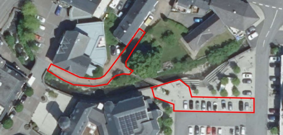 Hier sehen Sie ein Luftbild der Fußgängerbrücke über die Daade am Fontenay-De-Fleury Platz zum Schützenhof. Die rotmarkierten Felder sind Parkplätze und Gehwege, die durch den Brückenneubau gesperrt werden.