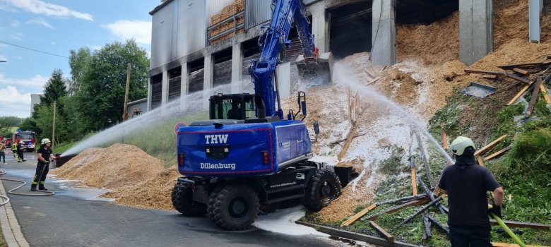 Hier sehen Sie einen Bagger des THWs, der die Späne aus dem Bunker zieht um Glutnester zu suchen.