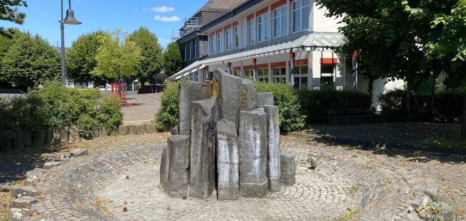 Hier sehen Sie den Dorfbrunnen von Weitefeld und im Hintergrund die Grundschule