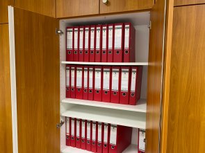 Hier sehen Sie einen geöffneten Büroschrank, in dem mehrere Ordner stehen