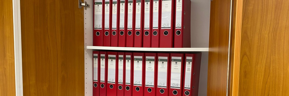 Ordner Hier sehen Sie einen geöffneten Büroschrank, in dem mehrere Ordner stehen