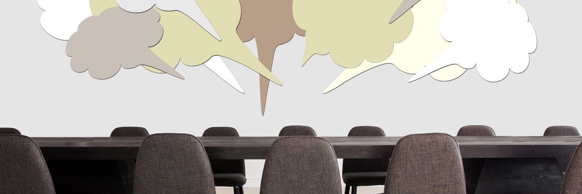 Meeting Hier sehen Sie einen leeren Sitzungssaal mit Sprechblasen, die über dem Tisch schweben.