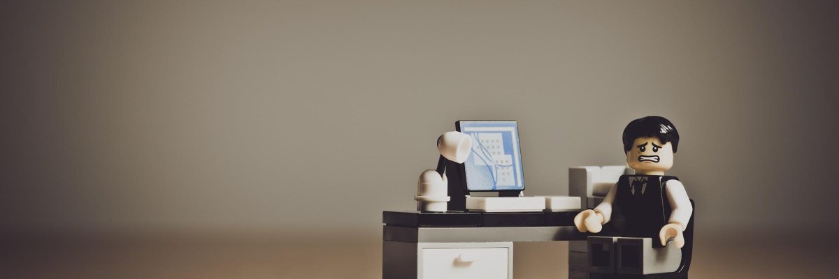 Hier sehen sie ein Lego-Männchen an einem Schreibtisch mit Computer, das verzweifelt guckt.