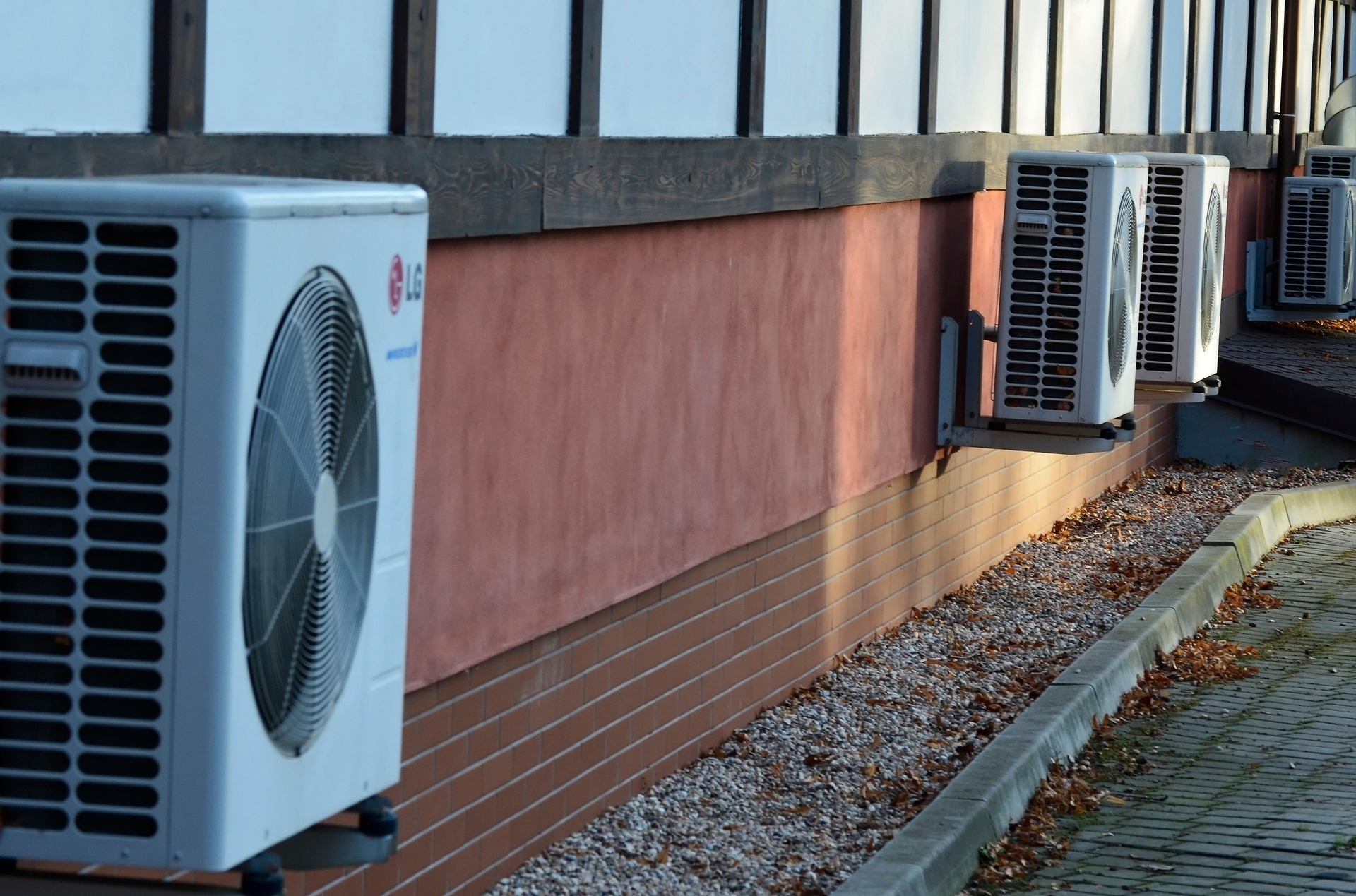 Hier sehen Sie drei Wärmepumpen, die an einer Hauswand angebracht sind.