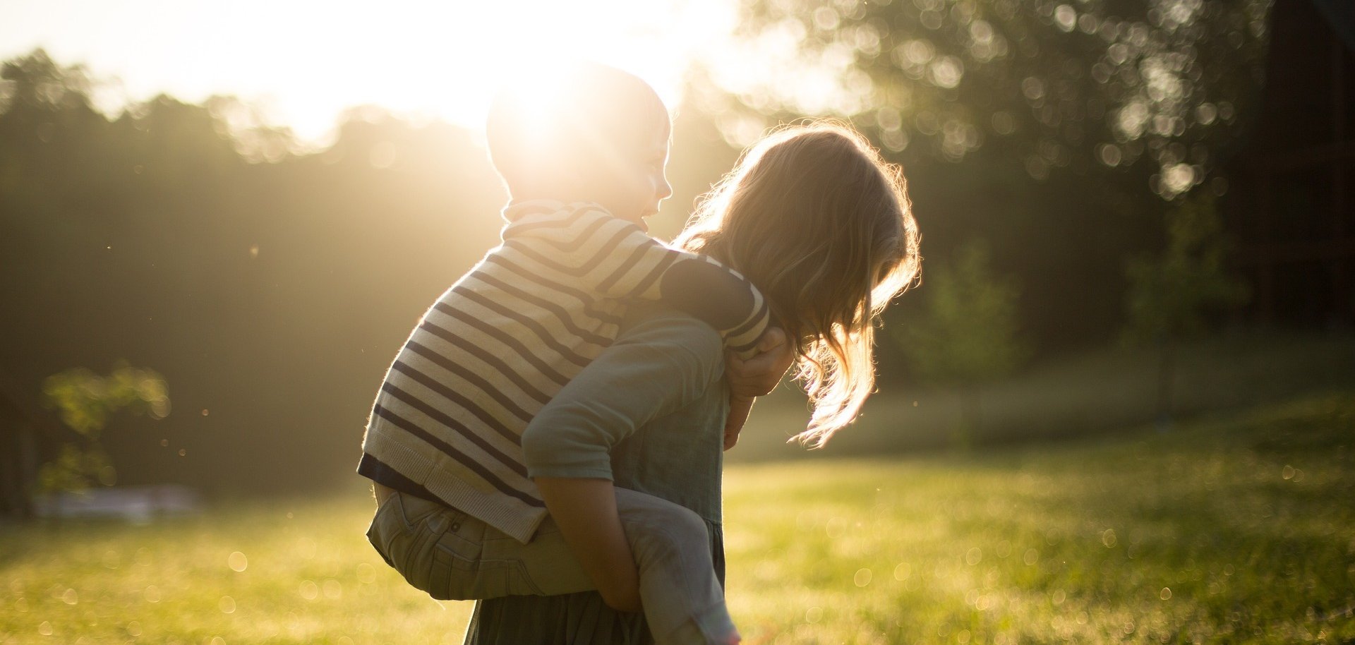 Hier sehen Sie zwei Kinder. Das eine trägt das andere Huckepack.