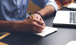 Notizen Hier sehen Sie einen Mann am Arbeitsplatz, der sich Notizen macht.