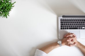 Arbeitsplatz Hier sehen Sie einen Schreibtisch mit Notebook, an dem eine Person arbeitet.