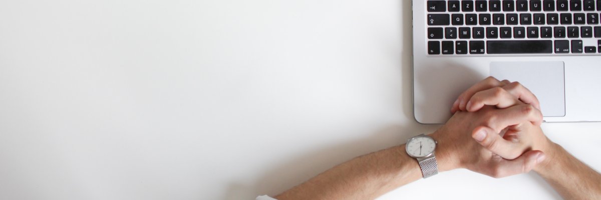 Hier sehen Sie einen Schreibtisch mit Notebook, an dem eine Person arbeitet.