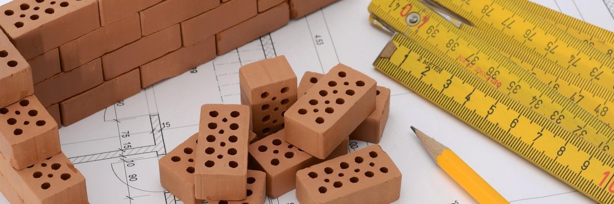 Bauen Hier sehen Sie einen Bauplan, auf dem Bausteine und ein Zollstock liegen.