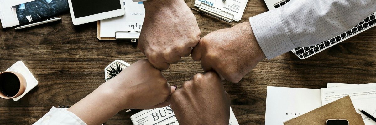 Hier sehen Sie vier Fäuste, die sich gegenseitig zu einem Gruß berühren.