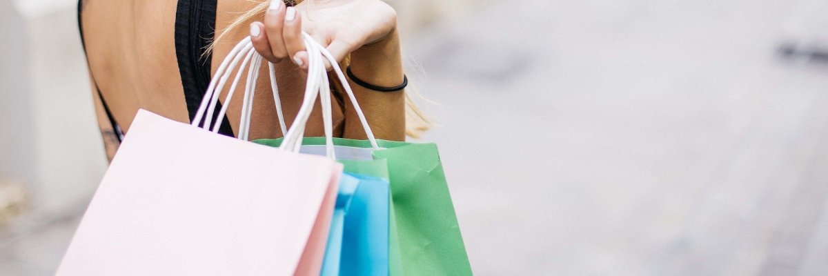 Hier sehen Sie eine Frau, die über ihrer Schulter mehrere Einkauftaschen trägt.